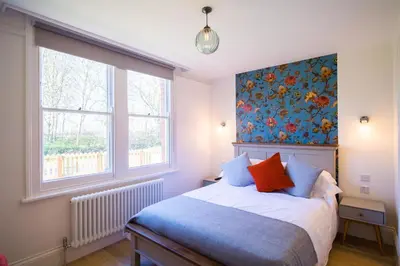 a bedroom with a bed with a floral wallpaper at Longstowe Farmhouse in Longstowe