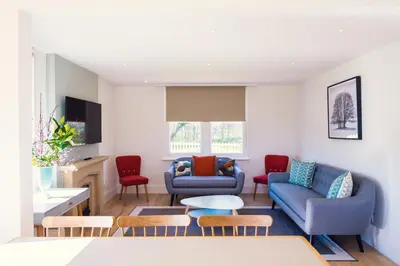 a living room with two blue couches and red chairs at Longstowe Farmhouse in Longstowe