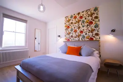 a bedroom with a large bed with a floral wall at Longstowe Farmhouse in Longstowe