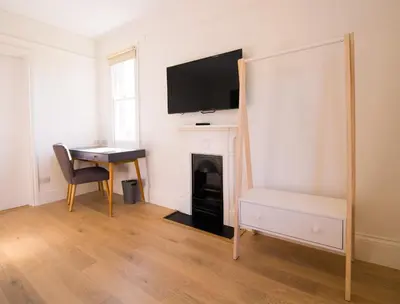 a living room with a desk and a tv above a fireplace at Longstowe Farmhouse in Longstowe
