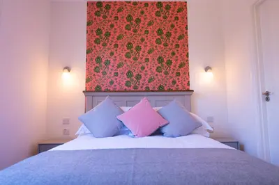 a bedroom with a bed with pink and blue pillows at Longstowe Farmhouse in Longstowe