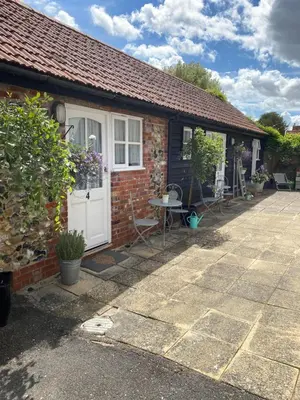 a brick cottage with a white door and a patio at Ship Stores B&B in Clare