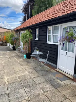a small black cottage with a table and a white door at Ship Stores B&B in Clare