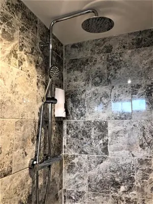 a bathroom with a shower with a stone wall at Eclipse Apartment No 1 in Newmarket