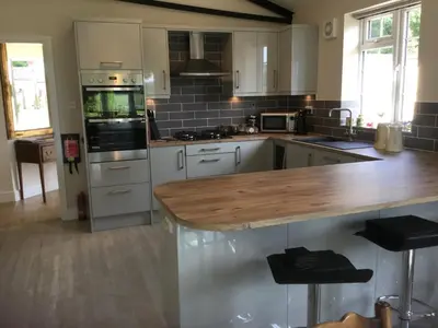 a kitchen with white cabinets and a wooden counter top at Eight ball house in Southburgh