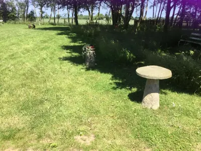 a stone bench sitting in the middle of a grass field at Eight ball house in Southburgh