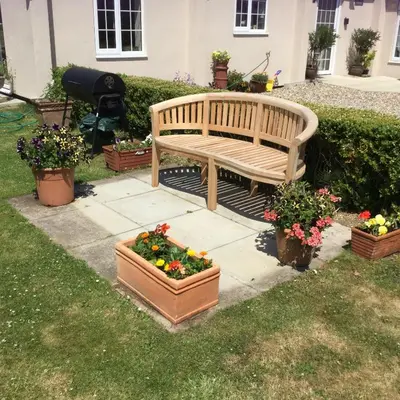 a wooden bench sitting in a yard with flowers at Eight ball house in Southburgh