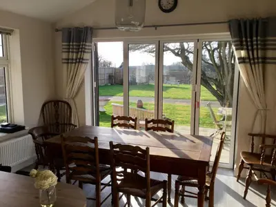 a dining room with a table and chairs and a large window at Eight ball house in Southburgh