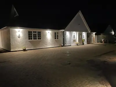 a white house with a driveway at night at The Thorpe Guesthouse in Huntingdon