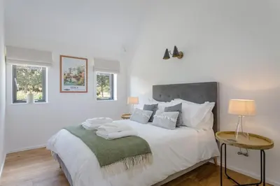 a bedroom with a large white bed with two tables at The Fieldbarns at Bullocks Farm in Bishops Stortford