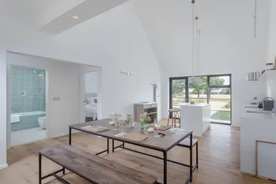 a kitchen and living room with a table and bench at The Fieldbarns at Bullocks Farm in Bishops Stortford