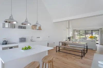 a white kitchen with a table and some chairs at The Fieldbarns at Bullocks Farm in Bishops Stortford