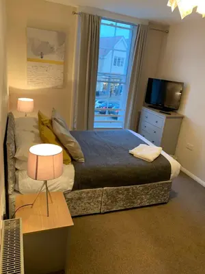a bedroom with a large bed and a window at Market Hill Apartments in Royston