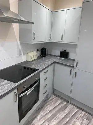 a white kitchen with white cabinets and a sink at Market Hill Apartments in Royston