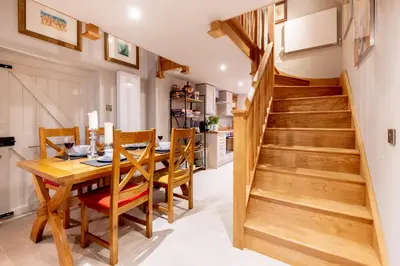a kitchen and dining room with a wooden table and stairs at Church Farm Lodge in Aldeburgh