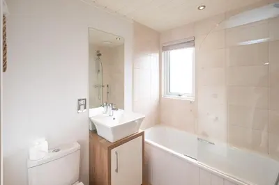 a bathroom with a sink and a tub and a toilet at Horizon Lodge in Sizewell