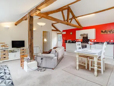 a living room with red walls and a table and a couch at The Hen House in Diss