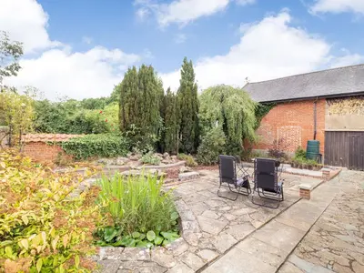 a patio with two chairs in a garden at The Hen House in Diss