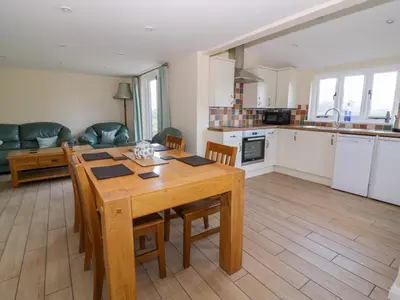 a kitchen and living room with a wooden table and chairs at The Granary in Halstead