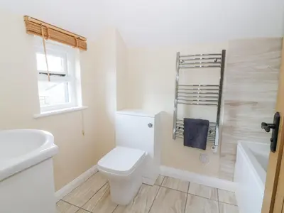 a white bathroom with a toilet and a sink at The Granary in Halstead