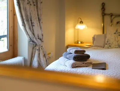 a mirror reflection of a bed with towels on it at Quavers Rest - quintessential little home & hot tub available ! in Rushford