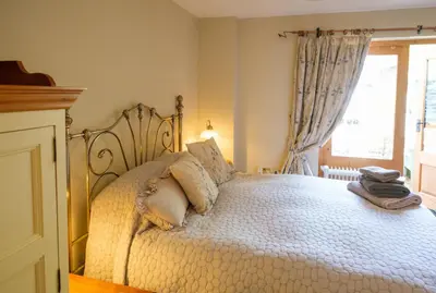 a bedroom with a large white bed with a window at Quavers Rest - quintessential little home & hot tub available ! in Rushford