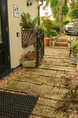 a wooden staircase leading to a house with plants at Quavers Rest - quintessential little home & hot tub available ! in Rushford