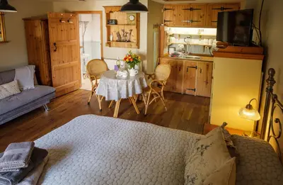 a living room with a table and a kitchen at Quavers Rest - quintessential little home & hot tub available ! in Rushford