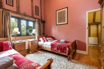 a bedroom with two beds and a window at Corner Farm Barn in Halesworth