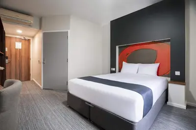 a bedroom with a large bed with a red painting on the wall at Ramada London Stansted Airport in Stansted Mountfitchet