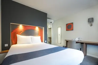a hotel room with a large bed and a desk at Ramada London Stansted Airport in Stansted Mountfitchet