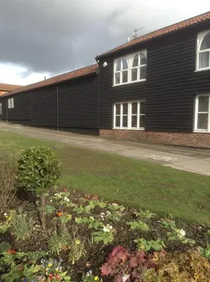 a black building with a garden in front of it at Little Bury Barn in Bury Saint Edmunds
