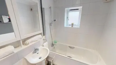 a white bathroom with a sink and a tub at Little Bury Barn in Bury Saint Edmunds