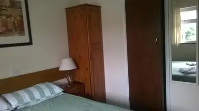 a bedroom with a bed and a cabinet and a lamp at Carlton Lodge in Cambridge