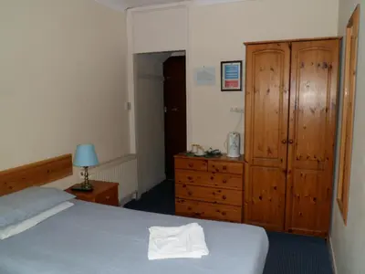 a bedroom with a bed and a dresser and a cabinet at Carlton Lodge in Cambridge