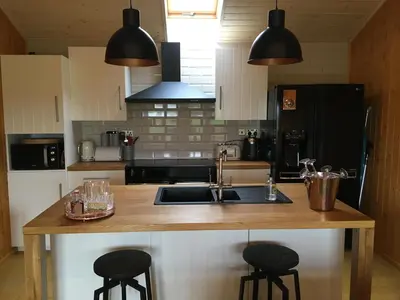 a kitchen with a sink and two bar stools at The Orchard Bramble Lodge in Hadleigh
