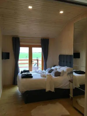 a bedroom with two beds and a large window at The Orchard Bramble Lodge in Hadleigh