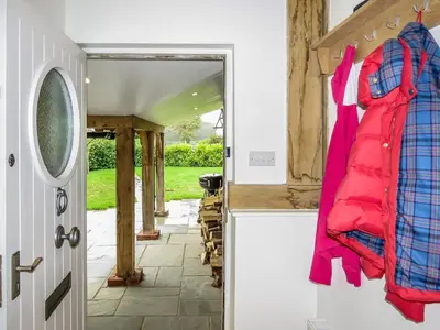 an open door with a red coat hanging on the wall at Meare House in Thorpeness