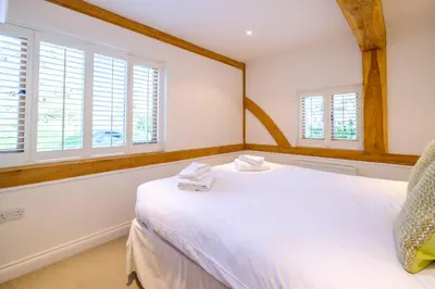 a bedroom with a large white bed with windows at Meare House in Thorpeness