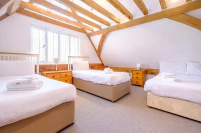 a attic room with two beds and a window at Meare House in Thorpeness