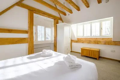 a bedroom with a white bed with two towels on it at Meare House in Thorpeness