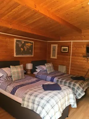 two beds in a room with wooden walls at The Theberton Lion in Theberton