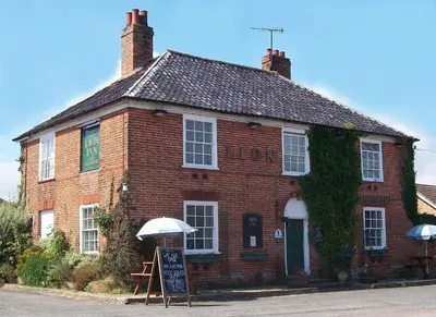a brick building with an umbrella in front of it at The Theberton Lion in Theberton