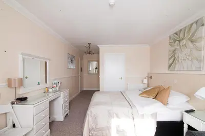 a white bedroom with a bed and a desk at Hunters Meet in Bishops Stortford