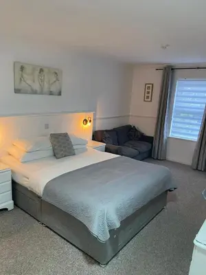 a bedroom with a large bed and a couch at Hunters Meet in Bishops Stortford