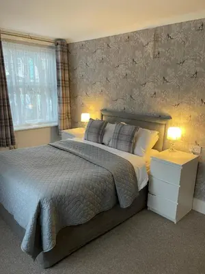 a bedroom with a large bed and two lamps at Hunters Meet in Bishops Stortford