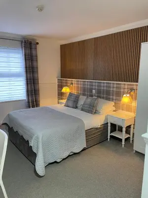 a bedroom with a large bed and a desk with two lamps at Hunters Meet in Bishops Stortford
