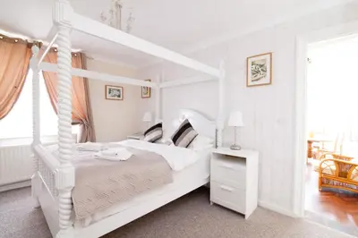 a white bedroom with a white canopy bed at Hunters Meet in Bishops Stortford