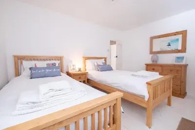 two beds in a room with wooden furniture at Puddleduck Cottage in Aldeburgh