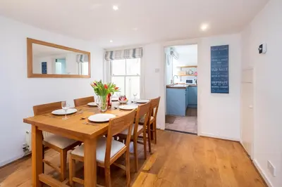 a dining room with a wooden table and chairs at Puddleduck Cottage in Aldeburgh